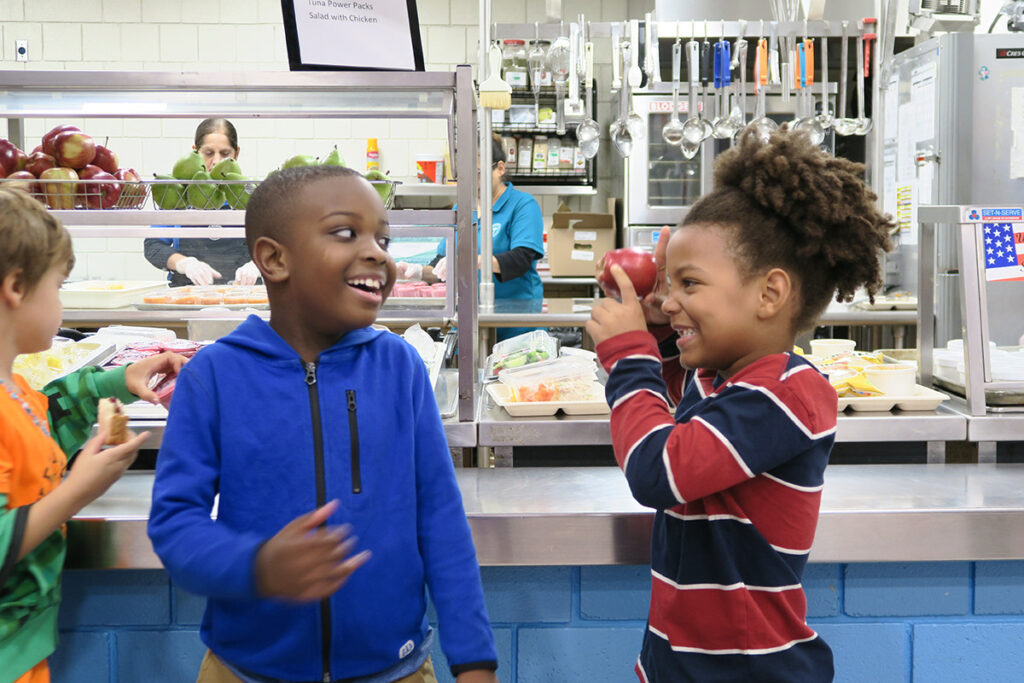 two students laugh while waiting for their school lunches