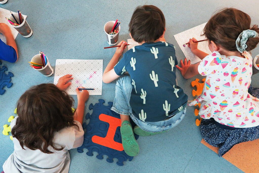 three students on the floor drawing
