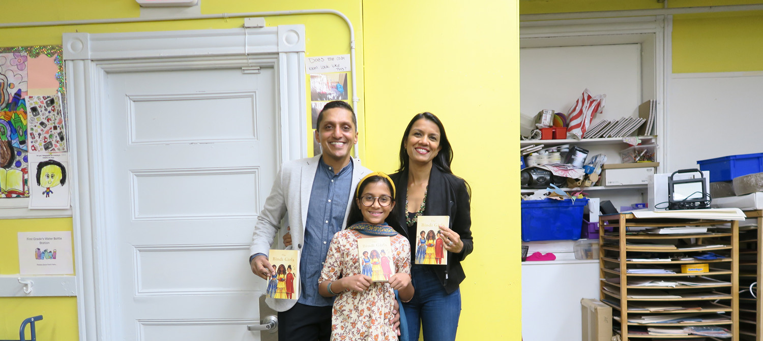 Family stands together holding books